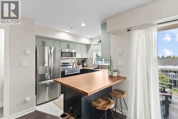 Kitchen featuring stainless steel appliances, wood countertops, and sage green cabinets. - 34 7370 Stride Avenue, Burnaby