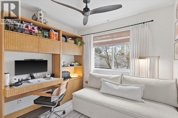 Office with a built-in wooden desk and shelving unit, and a white sofa. - 34 7370 Stride Avenue, Burnaby