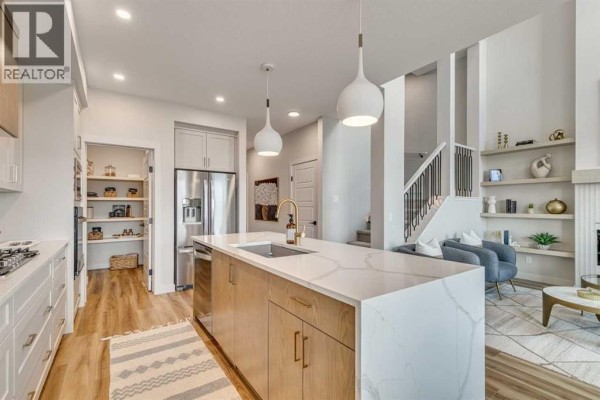 Open concept dining and living area with glass table, fireplace, and large windows. - 34 Amblefield Common Nw, Calgary