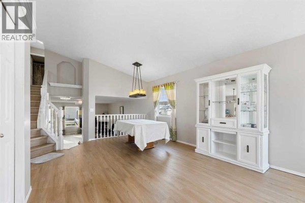 Living and dining area with light wood floors, white fireplace, and stairs leading to upper level. - 34 Applestone Park Se, Calgary