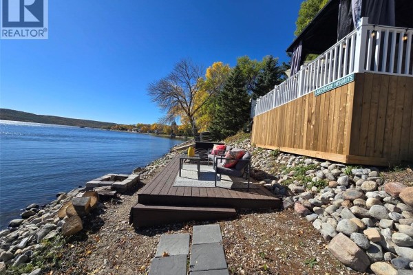 Deck with outdoor seating and a fire pit on the rocky shore of Crooked Lake. - 34 Bear Road, Crooked Lake