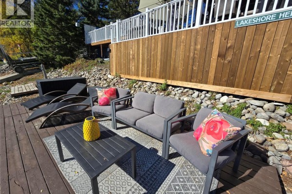 Outdoor seating area on a wooden dock with a coffee table and gray cushioned furniture. - 34 Bear Road, Crooked Lake