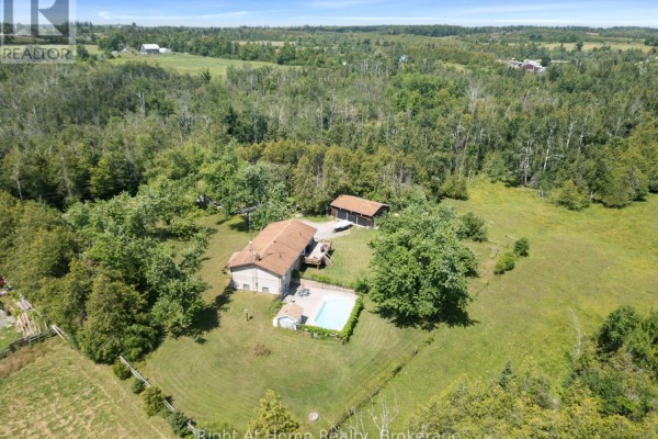 Aerial view of a house with a swimming pool and surrounding trees, with a detached garage visible. - 34 Birch Point Road, Kawartha Lakes