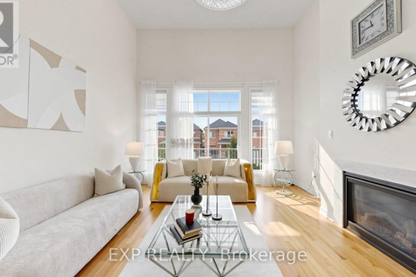 Living room with vaulted ceiling, fireplace, large windows, and light-colored furniture. - 34 Buttonleaf Crescent, Whitchurch Stouffville
