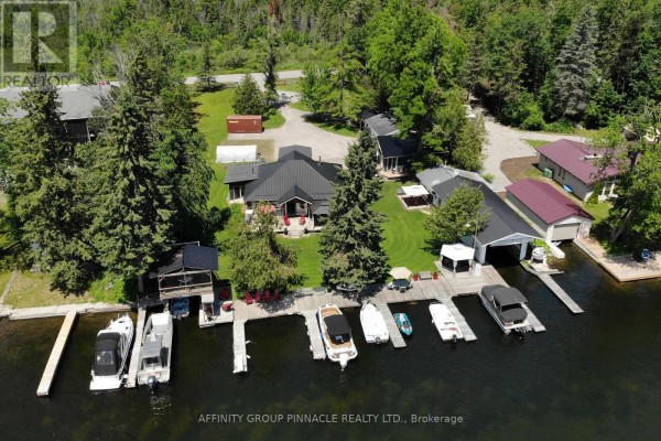 Aerial view of a property on a lake with multiple boats docked and several small buildings. - 34 Coldstream Road, Kawartha Lakes