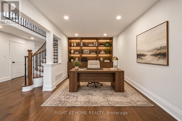 Home office with a wooden desk, office chair, built-in shelving, and hardwood floors. - 34 Dring Street, Ajax