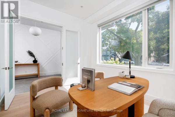 Home office with a wooden desk, chairs, and a large window overlooking a street. - 34 Edgecroft Road, Toronto