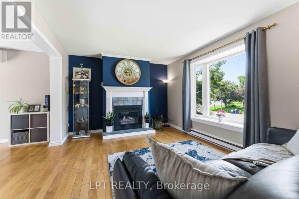 Living room featuring a dark blue accent wall with a fireplace, white mantle, and a large bay window. - 34 Fringewood Drive, Ottawa