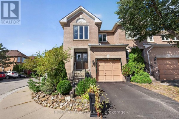 Bright kitchen with white cabinets, stainless steel appliances, and a wooden breakfast bar. - 34 Gilgorm Road, Brampton