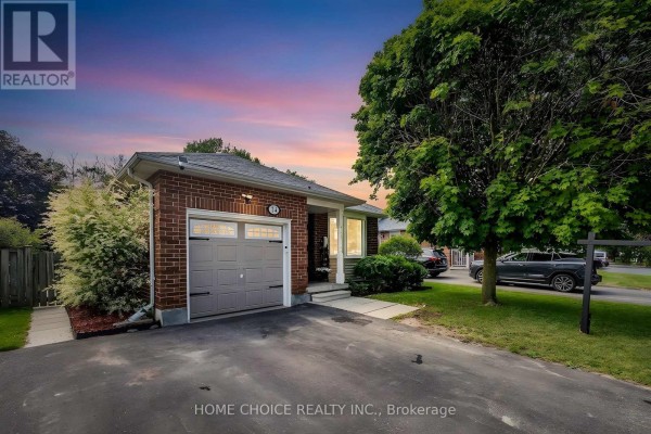 Dusk view of a brick bungalow with a garage, driveway, and a colorful sunset sky. - 34 Goldpine Avenue, Clarington