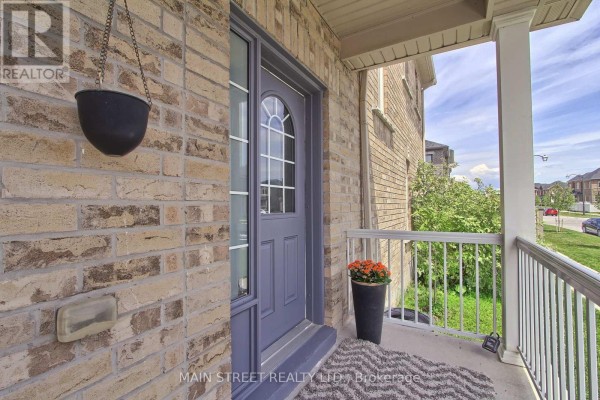 Front door of a brick townhouse with a grey door and a hanging basket. - 34 Grey Wing Avenue, Georgina
