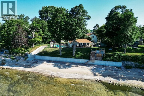 View of the house from the lakefront, showing a sandy beach and backyard. - 34 Hoover Point Lane, Selkirk