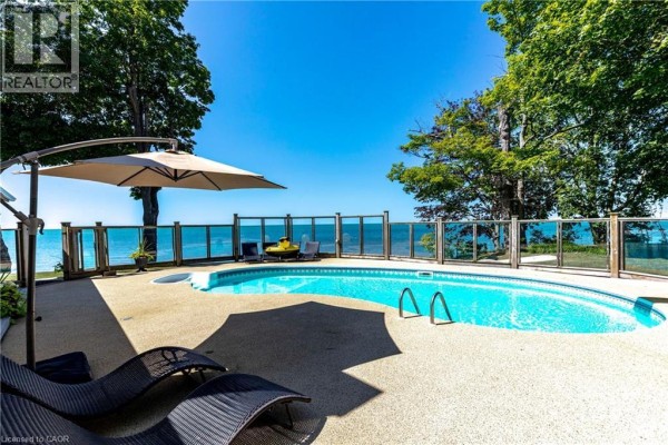 Poolside view with lounge chairs, umbrella, and water in the background. - 34 Hoover Point Lane, Selkirk