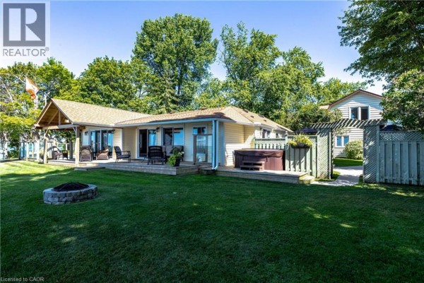 Rear exterior of the bungalow with a deck, hot tub, and lawn. - 34 Hoover Point Lane, Selkirk
