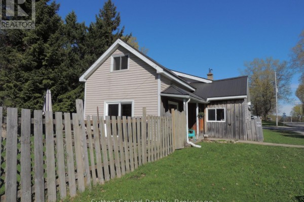 Close-up of the covered front porch with two teal chairs and a dark red door. - 34 Main Street, Arran Elderslie