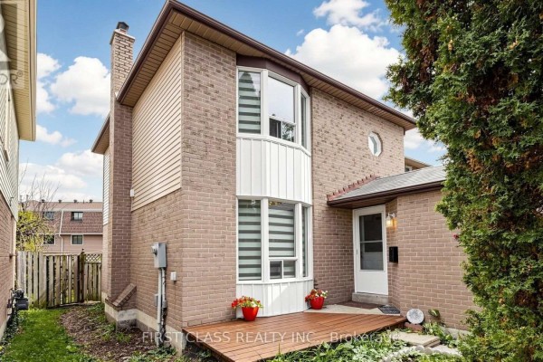 Side exterior of a brick house with a wooden deck and a bay window. - 34 Mayberry Court, Brampton