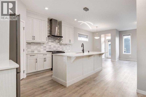Modern kitchen with white cabinets, a large island, and stainless steel appliances. - 34 Midtown  Sw, Airdrie