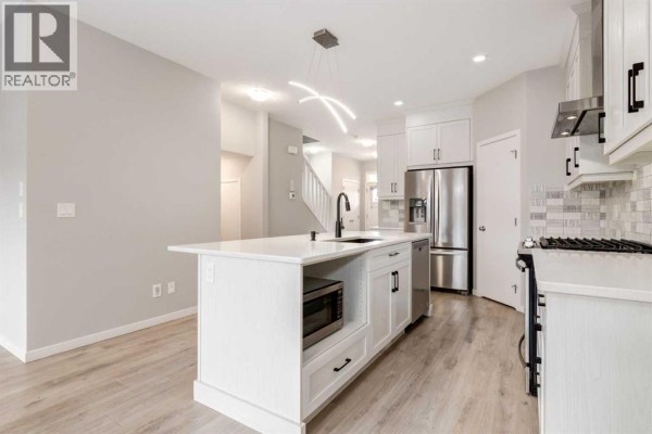 View of the kitchen island with a microwave and sink, facing towards the living area. - 34 Midtown  Sw, Airdrie