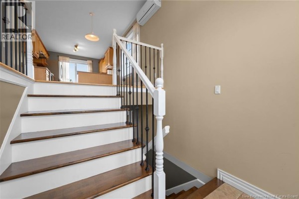 Interior staircase with white risers, dark wood treads, white railing, and black spindles. - 34 Monique Street, Moncton