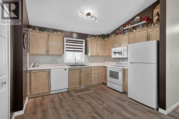 Kitchen with light wood cabinets, white appliances, light grey countertops, and dark brown walls. - 34 Mt Aberdeen Link Se, Calgary