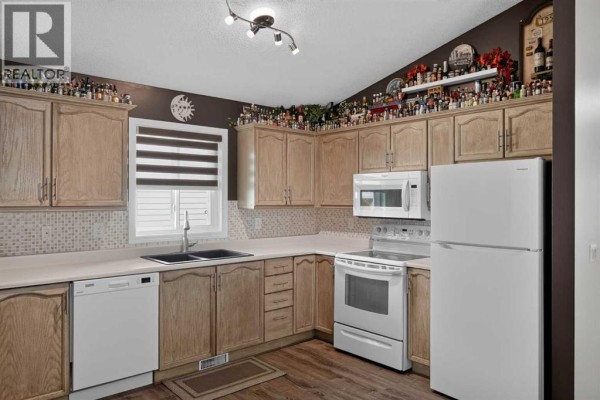 Kitchen featuring light oak cabinets, a white refrigerator, a white stove, and a window with blinds. - 34 Mt Aberdeen Link Se, Calgary