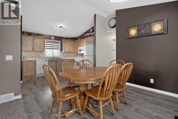 Dining area with a wooden table and chairs, adjacent to a kitchen with light wood cabinets. - 34 Mt Aberdeen Link Se, Calgary