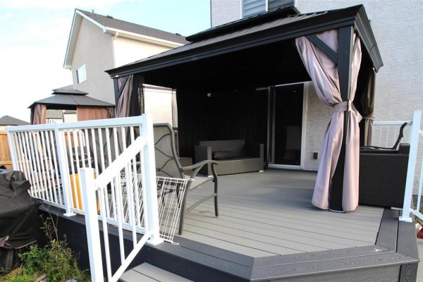 Backyard deck with gray composite flooring, a white railing, and a covered outdoor seating area. - 34 Red Wing Cove, Winnipeg