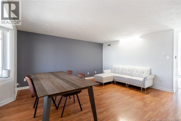 Living and dining area with a wood table, chairs, and white sectional sofa. - 34 Rennick Road, Moncton