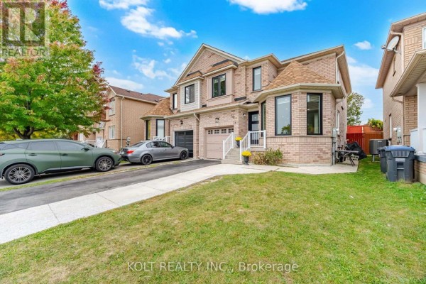 Side exterior view of a brick house with a double garage and a large green lawn. - 34 Saddleback Square, Brampton