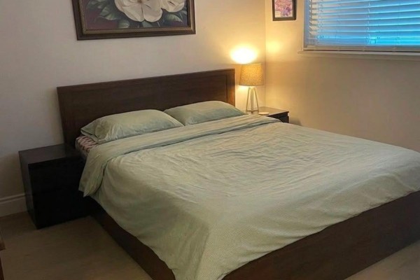 Bedroom with a wooden bed frame, green bedding, and two dark wood nightstands. - 34 Watson Crescent, Brampton
