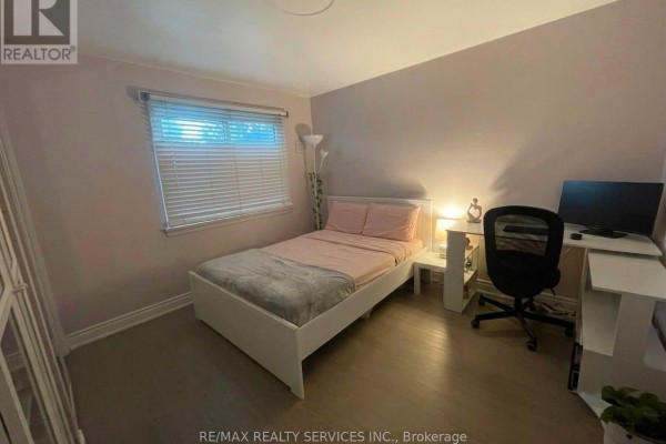 Bedroom with a white bed frame, pink bedding, a white desk, and computer setup. - 34 Watson Crescent, Brampton