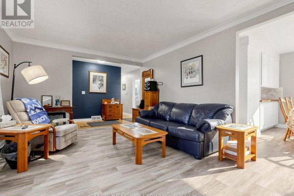 Living room with a navy wall, seating area, and an open doorway revealing a kitchen area. - 340 Boyer Street, Whitchurch Stouffville