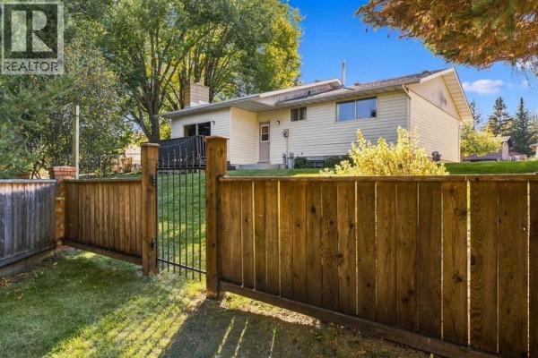 Gravel driveway leading to the side of the beige and cream bungalow with a green lawn. - 340 Canniff Place Sw, Calgary