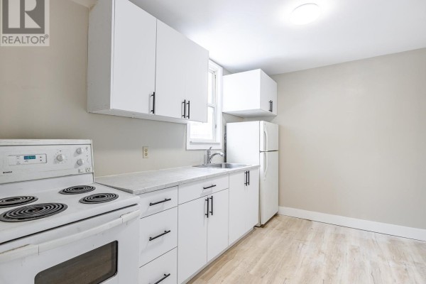White kitchen cabinets and appliances including a stove, refrigerator, and sink. - 340 Wellington St, Sault Ste  Marie