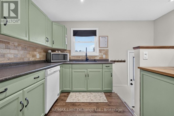 Kitchen area with light green cabinets, dark countertops, a window with a black blind, and a dishwasher. - 3400 Highway 9 Highway, Brockton