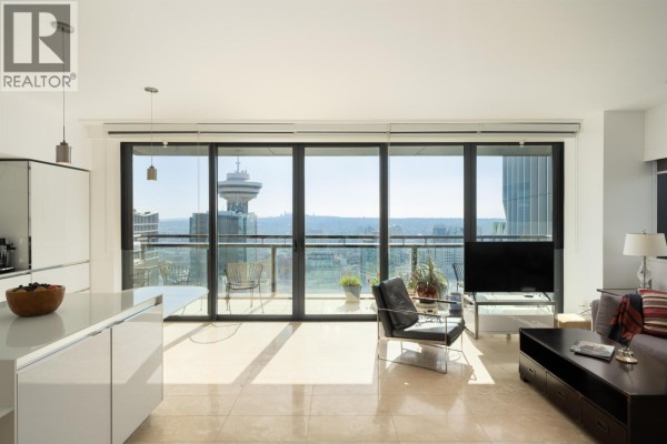 Open concept living space with white kitchen island, seating area, and expansive windows with city panorama. - 3403 838 W Hastings Street, Vancouver