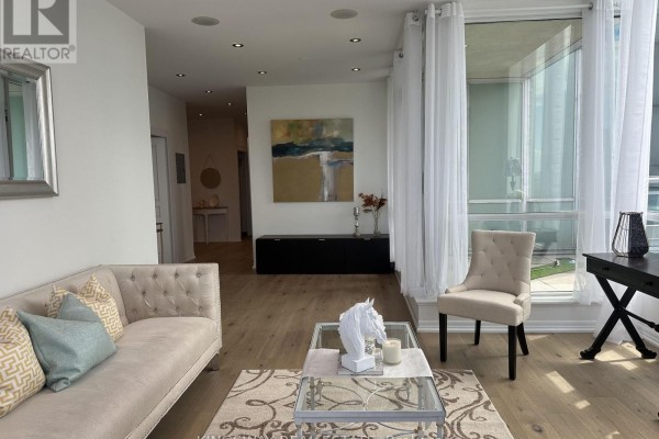 Living area with beige sofa, glass coffee table, and artwork. - 3404 - 220 Burnhamthorpe Road W, Mississauga