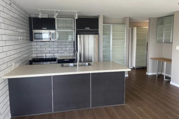 Kitchen island with beige countertop and dark cabinets, stainless steel appliances, and white subway tile backsplash. - 3404 13688 100 Ave, Surrey