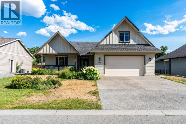 Front exterior of a beige house with a double garage door and green lawn. - 3404 Mckechnie Drive, Armstrong