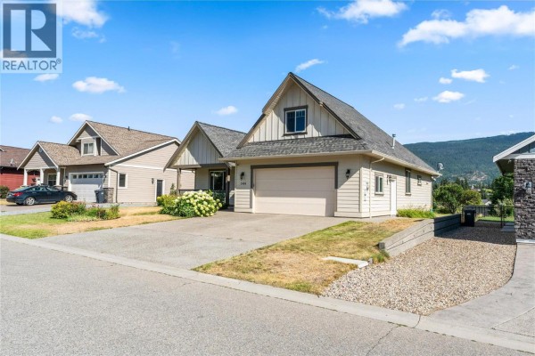 Front and side exterior of a beige house with a grey roof and mountain view. - 3404 Mckechnie Drive, Armstrong