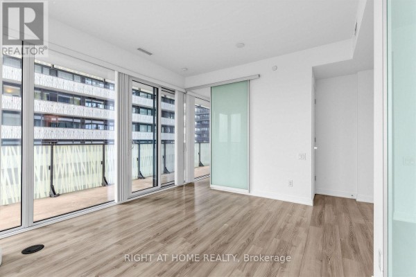 View of the living area, kitchen, and balcony with glass doors and light floors. - 3408 - 42 Charles Street E, Toronto