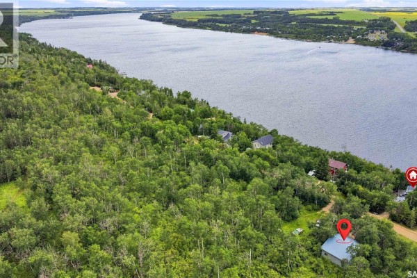 Aerial view of a vast landscape showing a wide lake, forested hills, and scattered houses. - 3409 East Nickorick Beach, Wakaw Lake