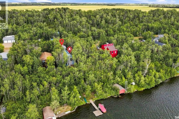 Aerial view of waterfront properties surrounded by lush trees, featuring docks and boats on the lake. - 3409 East Nickorick Beach, Wakaw Lake