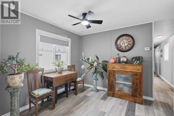 Dining area with a small wooden table, two chairs, and a decorative cabinet against a grey wall. - 341, 5344 76 Street, Red Deer