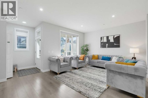 Living room with grey velvet tufted sofas, a plush rug, and light wood flooring. - 341 Calhoun Common Ne, Calgary