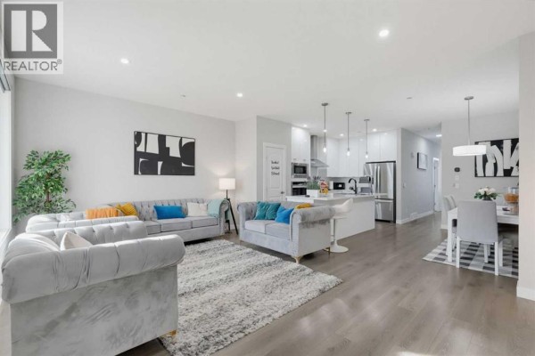 Open concept living, dining, and kitchen area with light grey walls and white cabinets. - 341 Calhoun Common Ne, Calgary