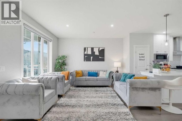 Spacious living area with large windows overlooking the backyard and an open flow to the kitchen. - 341 Calhoun Common Ne, Calgary