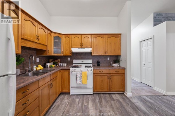Kitchen with natural wood cabinets, laminate flooring, and white appliances. - 341 Rockport Lane, Kingsville