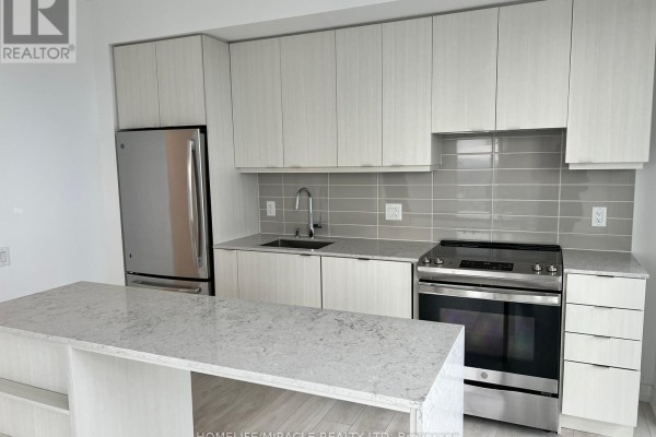 A modern kitchen with light wood cabinets, white quartz countertops, stainless steel appliances and an island. - 3410 - 4065 Confederation Parkway, Mississauga