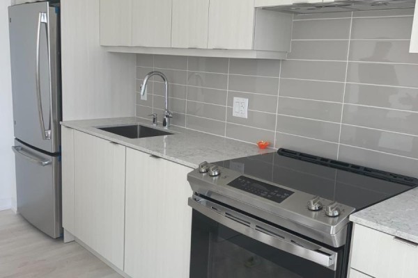 A close-up view of a contemporary kitchen with light wood cabinetry and stainless steel appliances. - 3410 - 4065 Confederation Parkway, Mississauga